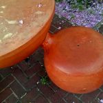 Close -up photo of bright orange bulbous table and attached seat of a Baltimore street